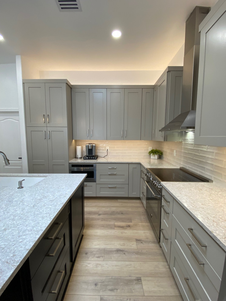 Mid-sized transitional l-shaped vinyl floor and beige floor eat-in kitchen photo in Phoenix with an undermount sink, shaker cabinets, gray cabinets, quartz countertops, white backsplash, ceramic backsplash, stainless steel appliances, an island and white countertops