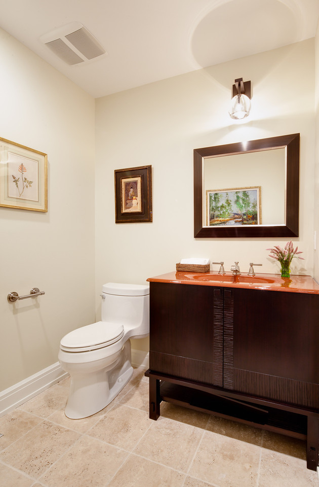 Photo of a mid-sized traditional powder room in New York with furniture-like cabinets, dark wood cabinets, a one-piece toilet, beige walls, porcelain floors, an integrated sink and orange benchtops.