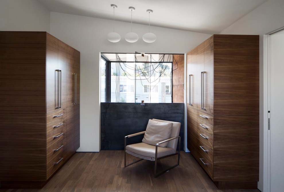 Photo of a modern gender-neutral storage and wardrobe in San Francisco with flat-panel cabinets and medium wood cabinets.