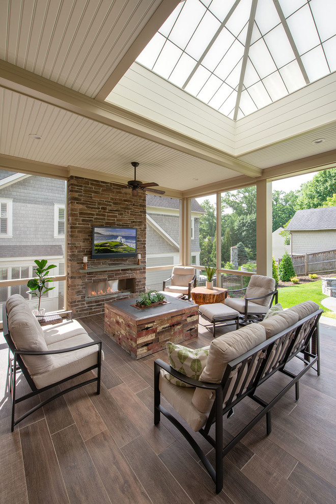 Inspiration for a large traditional backyard screened-in verandah in DC Metro with natural stone pavers and a roof extension.