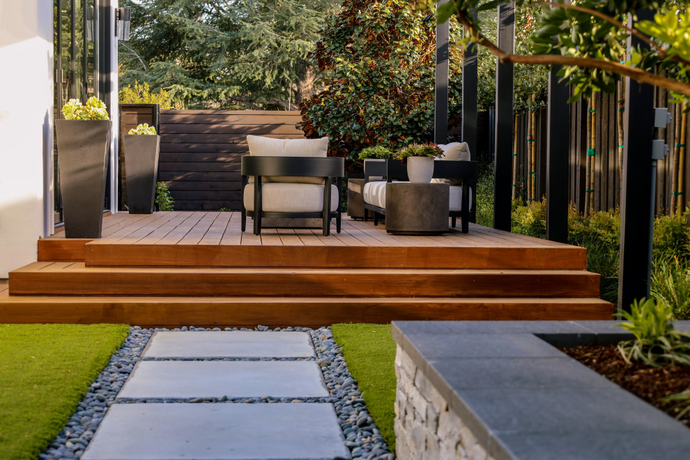 Cette image montre une terrasse en bois arrière design avec un foyer extérieur et une pergola.