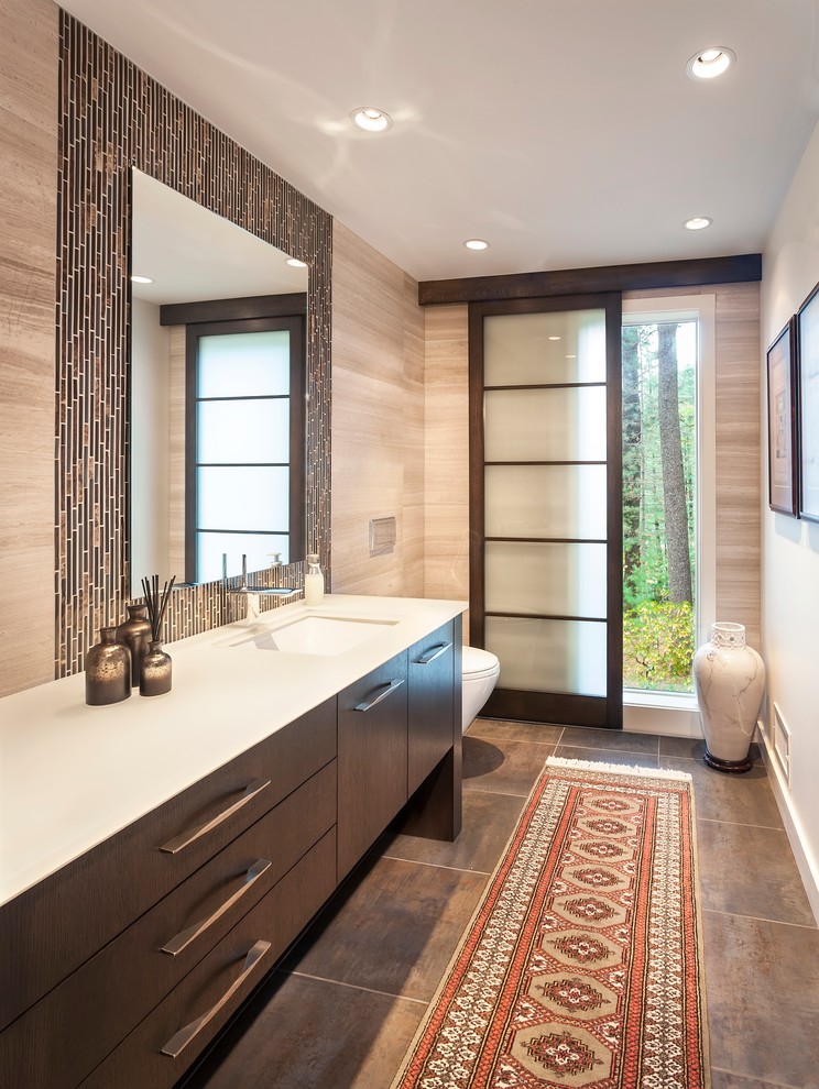 Inspiration for a contemporary powder room in Boston with an undermount sink, flat-panel cabinets, dark wood cabinets, brown tile, beige tile and white benchtops.