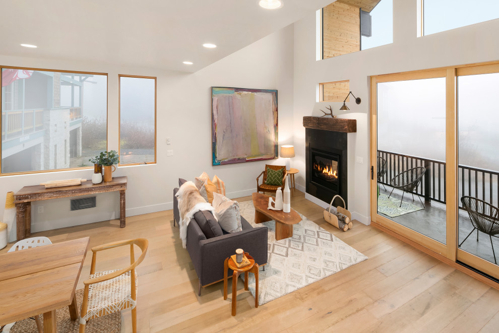 This is an example of a contemporary open concept living room in Seattle with white walls, light hardwood floors and a corner fireplace.