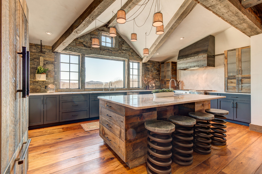 This is an example of a country u-shaped kitchen in Boston with an undermount sink, shaker cabinets, blue cabinets, stone tile splashback, stainless steel appliances, medium hardwood floors, with island and beige benchtop.