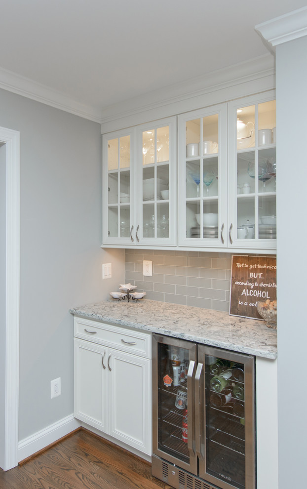 Inspiration for a large transitional l-shaped dark wood floor and brown floor kitchen remodel in Baltimore with a farmhouse sink, recessed-panel cabinets, white cabinets, quartz countertops, gray backsplash, subway tile backsplash, stainless steel appliances and an island