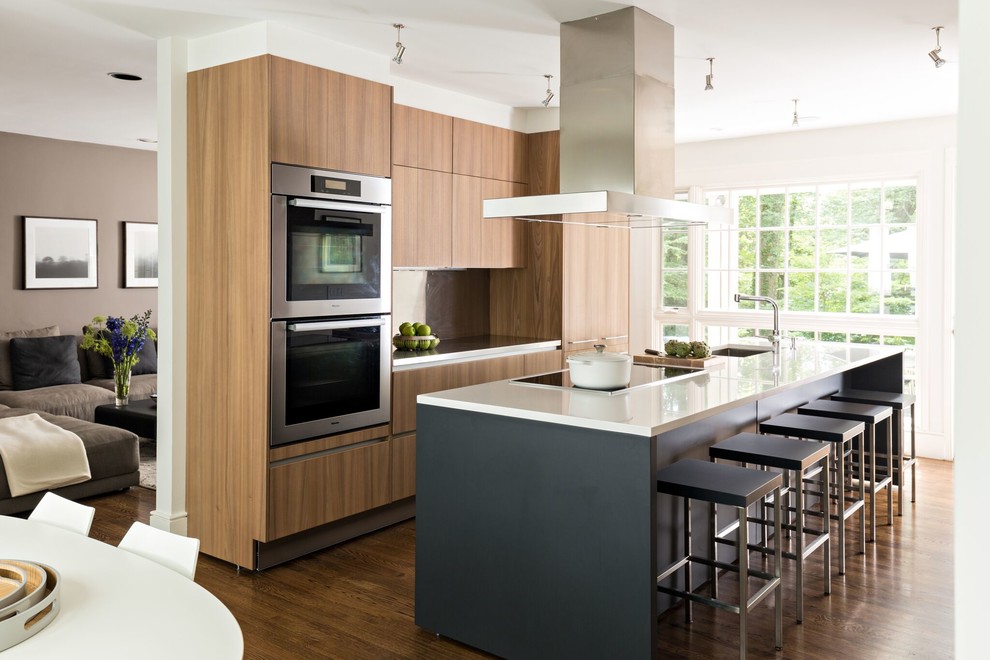 Inspiration for a contemporary galley kitchen in Boston with an undermount sink, flat-panel cabinets, medium wood cabinets, brown splashback, panelled appliances, medium hardwood floors, with island, brown floor and white benchtop.
