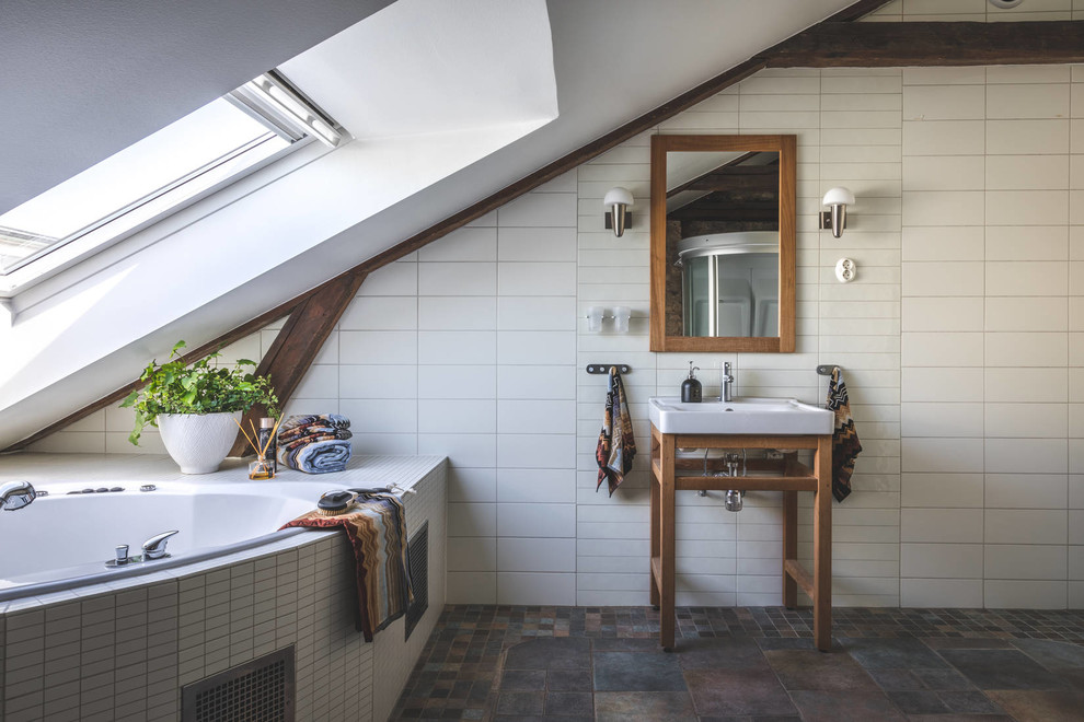 Inspiration for a mid-sized mediterranean master bathroom in Gothenburg with a corner tub, white tile, cement tile, white walls, a console sink and brown floor.