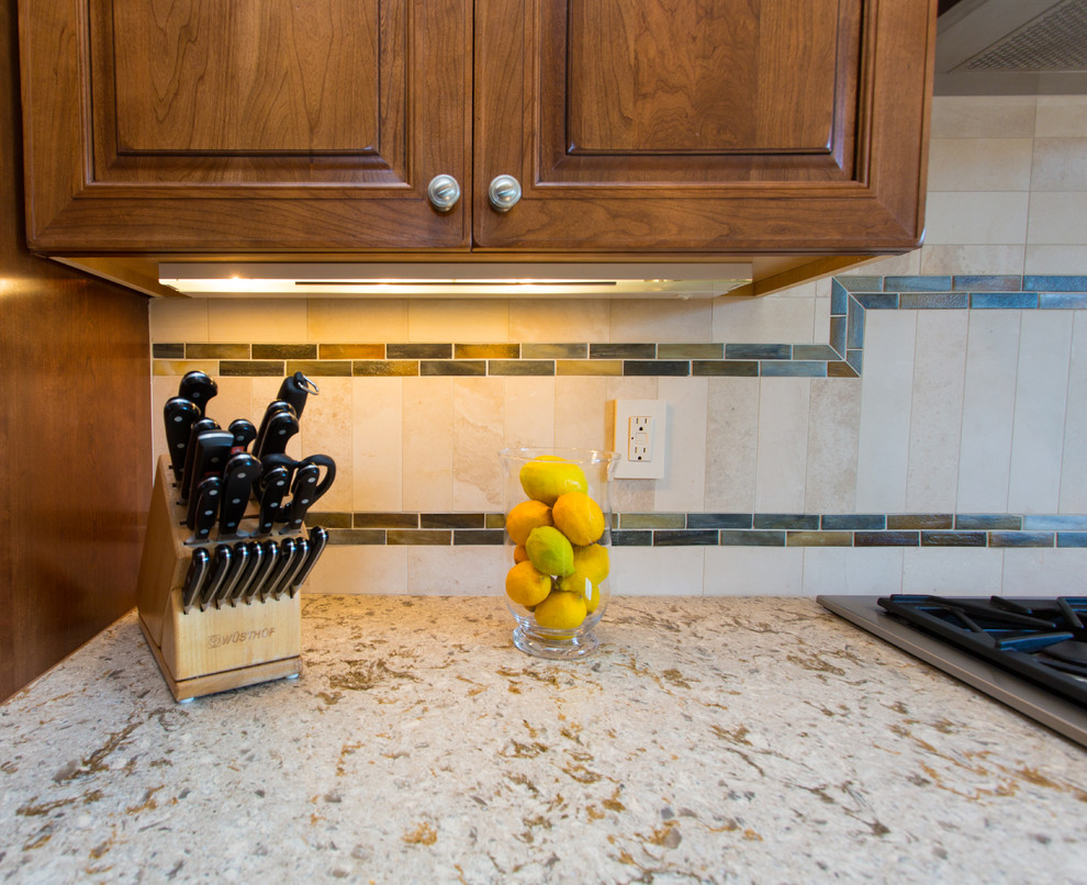 Large transitional l-shaped medium tone wood floor and brown floor eat-in kitchen photo in Denver with a farmhouse sink, raised-panel cabinets, medium tone wood cabinets, granite countertops, beige backsplash, stone tile backsplash, stainless steel appliances and an island