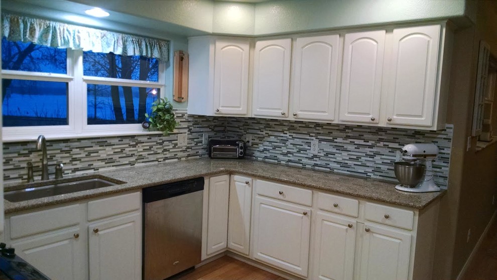 Mid-sized transitional u-shaped light wood floor enclosed kitchen photo in Denver with an undermount sink, raised-panel cabinets, white cabinets, granite countertops, multicolored backsplash, matchstick tile backsplash, stainless steel appliances and no island