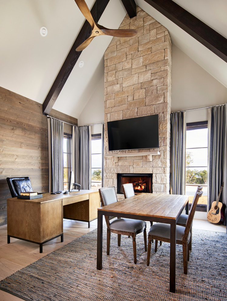 Transitional study room in Other with white walls, light hardwood floors, a standard fireplace, a stone fireplace surround, a freestanding desk and beige floor.
