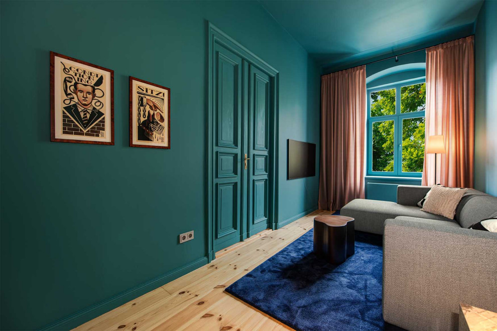 Wohnzimmer With blauer Wandfarbe, hellem Holzboden and TV-Wand in Berlin