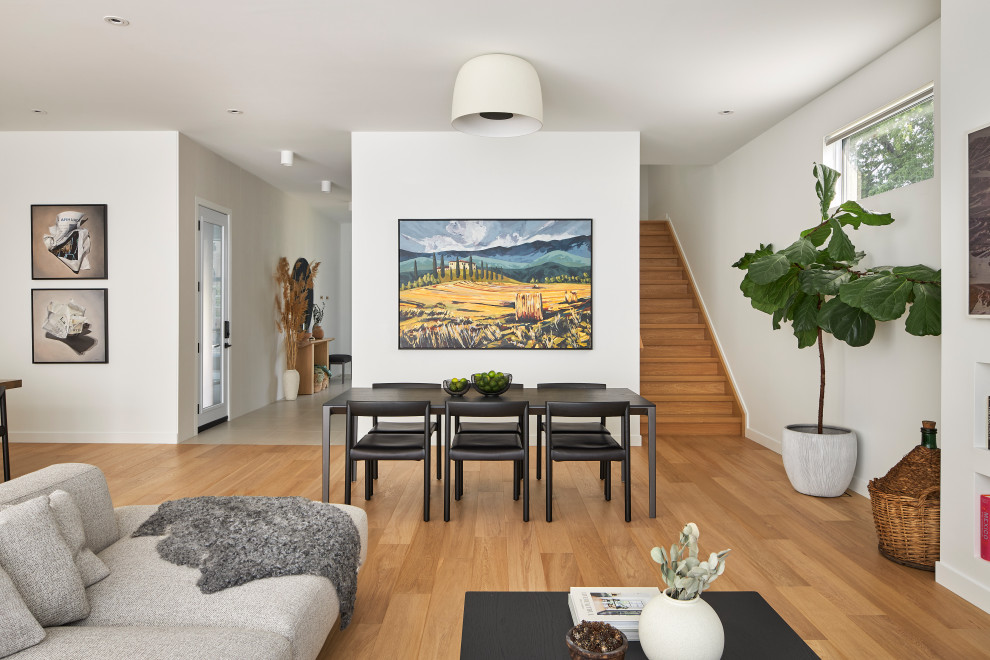 Modelo de salón abierto escandinavo con paredes blancas, suelo de madera clara, estufa de leña y televisor colgado en la pared
