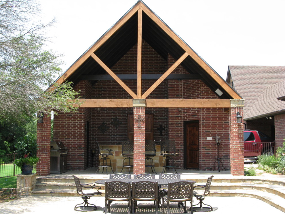 This is an example of a country patio in Dallas with an outdoor kitchen, brick pavers and an awning.
