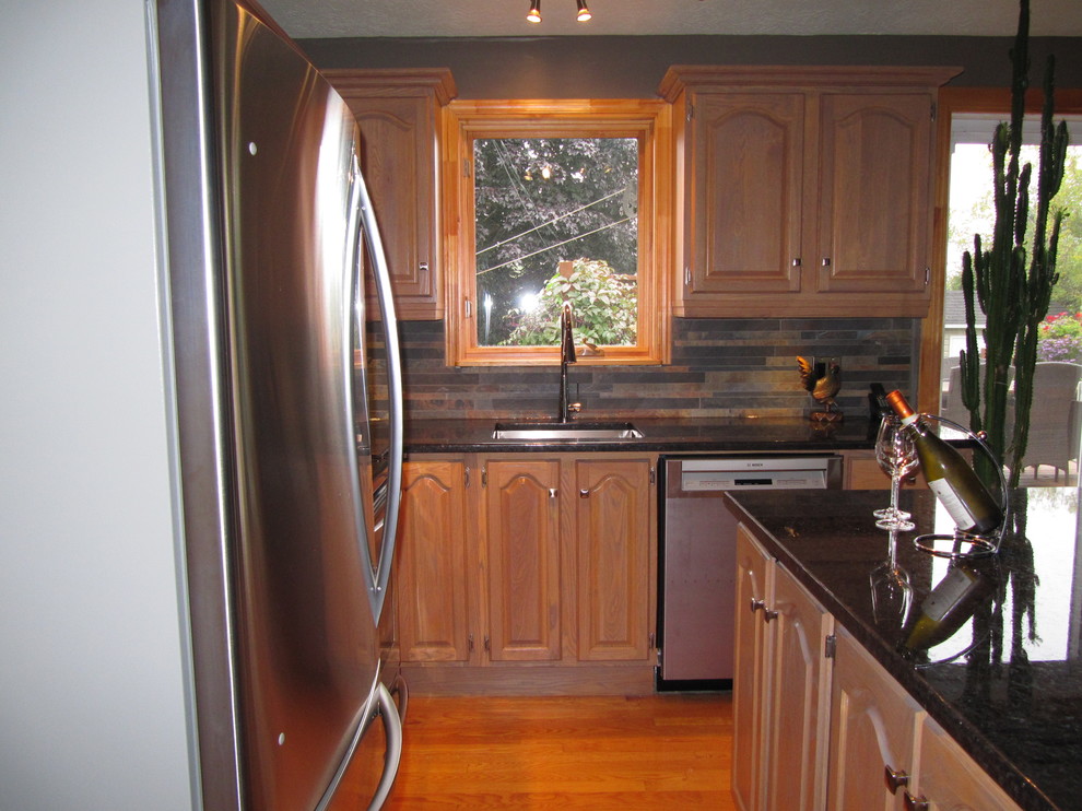 Small country l-shaped eat-in kitchen in Montreal with an undermount sink, louvered cabinets, light wood cabinets, granite benchtops, multi-coloured splashback, porcelain splashback, stainless steel appliances, light hardwood floors and with island.