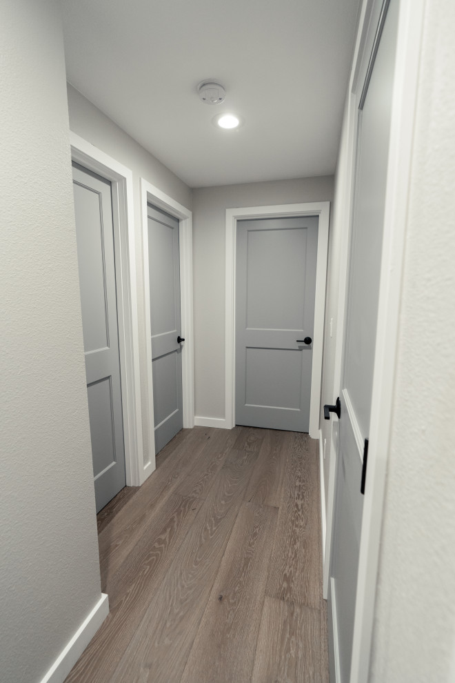 Inspiration pour un couloir traditionnel de taille moyenne avec un mur gris, parquet clair et un sol marron.