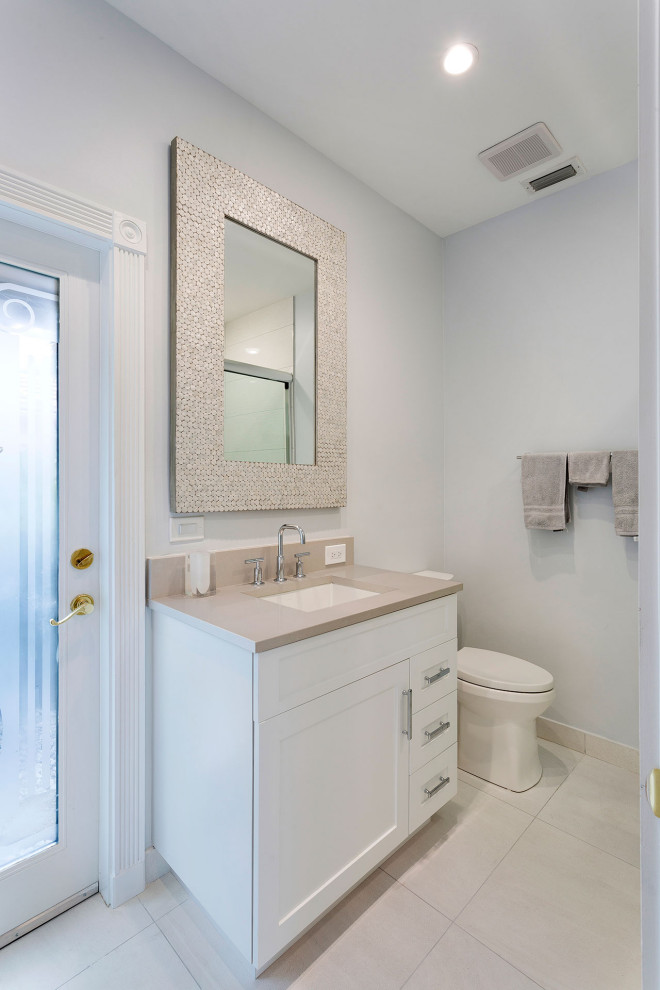 Example of a mid-sized transitional 3/4 porcelain tile and beige floor bathroom design in Miami with shaker cabinets, white cabinets, a one-piece toilet, beige walls, an undermount sink, solid surface countertops and beige countertops