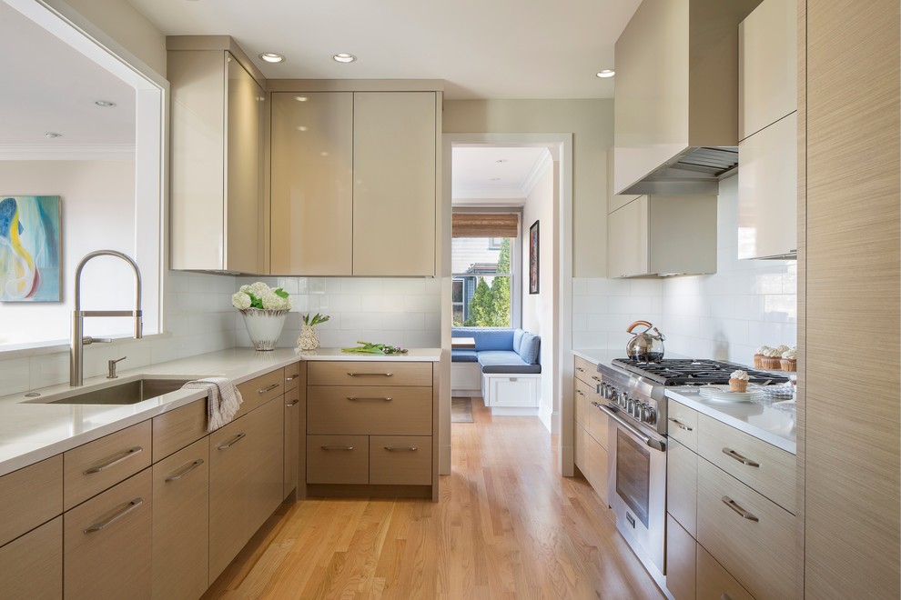 Design ideas for a contemporary galley separate kitchen in Boston with an undermount sink, flat-panel cabinets, quartz benchtops, white splashback, glass tile splashback, light hardwood floors, no island, light wood cabinets and panelled appliances.