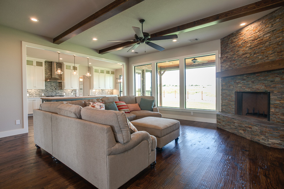 Large country open concept living room in Dallas with beige walls, medium hardwood floors, a corner fireplace, a stone fireplace surround and a wall-mounted tv.