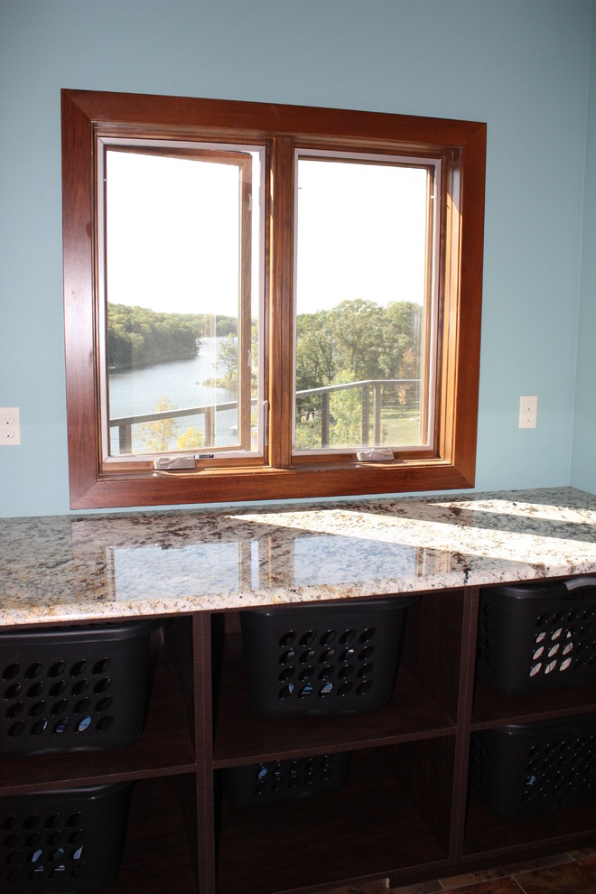 Inspiration for a large transitional galley vinyl floor and multicolored floor utility room remodel with an utility sink, recessed-panel cabinets, medium tone wood cabinets, laminate countertops, blue walls and a side-by-side washer/dryer
