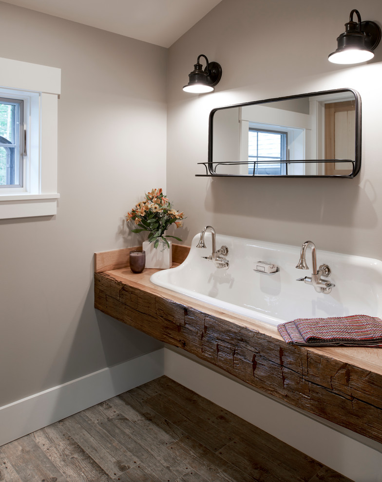 Inspiration for a mid-sized country bathroom in Detroit with open cabinets, distressed cabinets, a drop-in tub, a shower/bathtub combo, a two-piece toilet, beige walls, porcelain floors, a trough sink, wood benchtops, grey floor, a shower curtain and brown benchtops.