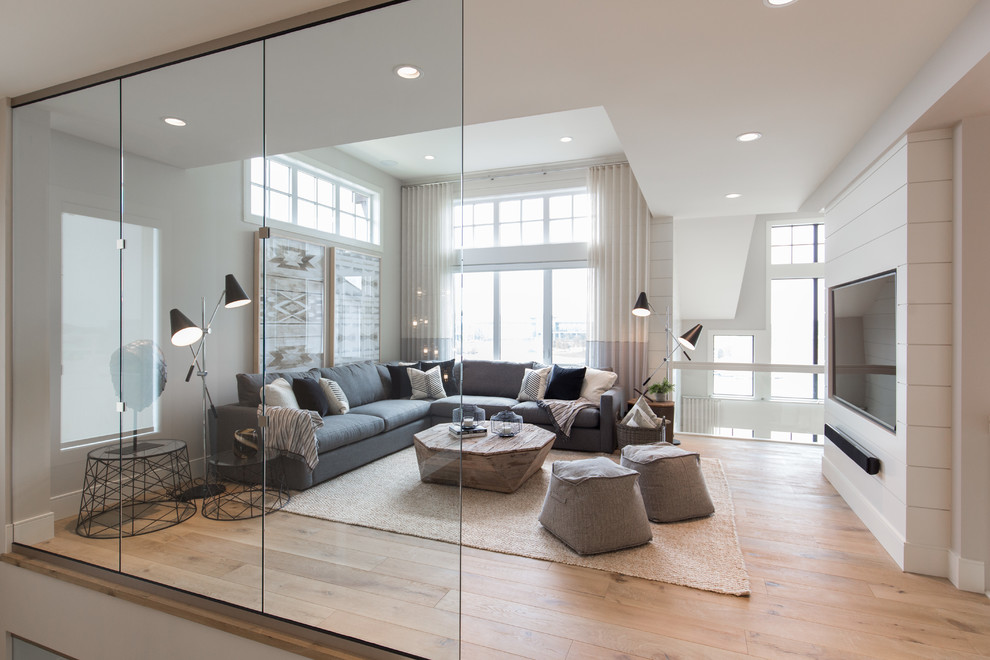 Large farmhouse open concept medium tone wood floor and brown floor family room photo in Calgary with white walls and a wall-mounted tv