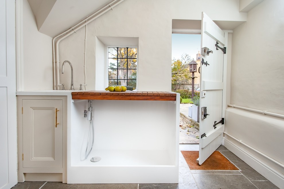 This is an example of a mid-sized traditional u-shaped eat-in kitchen in Gloucestershire with a double-bowl sink, recessed-panel cabinets, dark wood cabinets, marble benchtops, white splashback, marble splashback, stainless steel appliances, with island, grey floor and white benchtop.