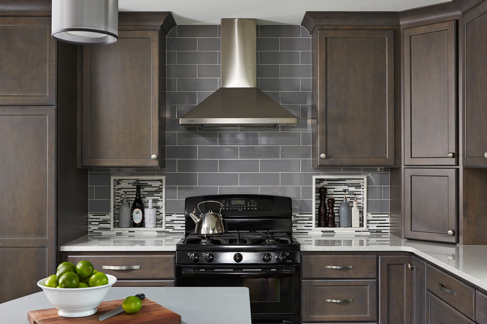 This is an example of a transitional kitchen in Minneapolis with recessed-panel cabinets, dark wood cabinets, grey splashback, subway tile splashback, black appliances and with island.