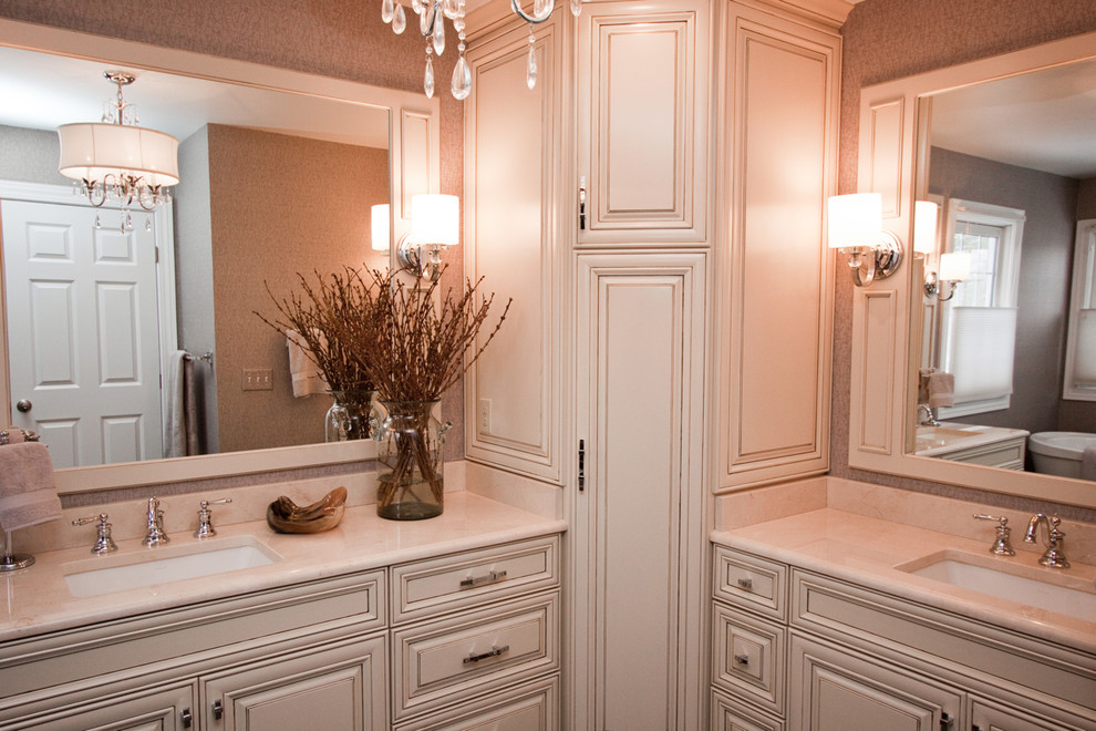Mid-sized traditional master bathroom in Cleveland with raised-panel cabinets, beige cabinets, a freestanding tub, a corner shower, a two-piece toilet, beige tile, stone slab, grey walls, ceramic floors, an undermount sink, solid surface benchtops, brown floor and a hinged shower door.