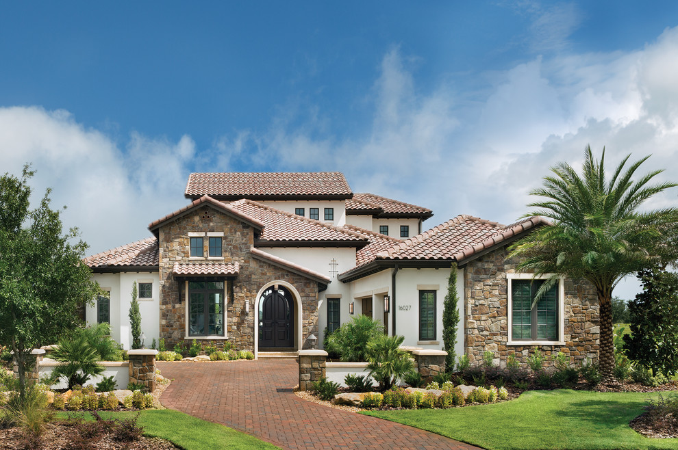 This is an example of an expansive mediterranean two-storey exterior in Tampa with mixed siding.