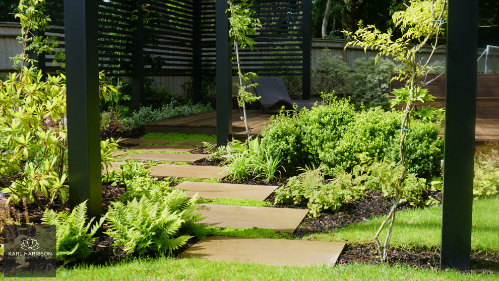 Imagen de jardín minimalista grande en verano en patio trasero con jardín francés, parterre de flores, exposición total al sol, entablado y con madera