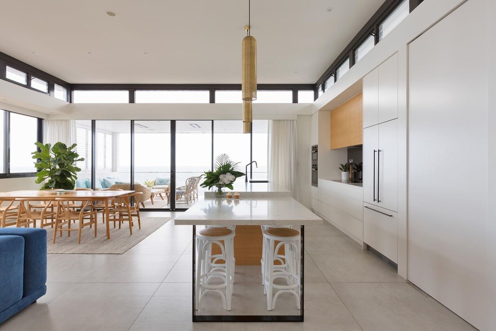 Photo of a contemporary galley open plan kitchen in Sydney with a drop-in sink, black appliances, ceramic floors, multiple islands, grey floor, flat-panel cabinets, white cabinets, marble benchtops, multi-coloured benchtop and mirror splashback.