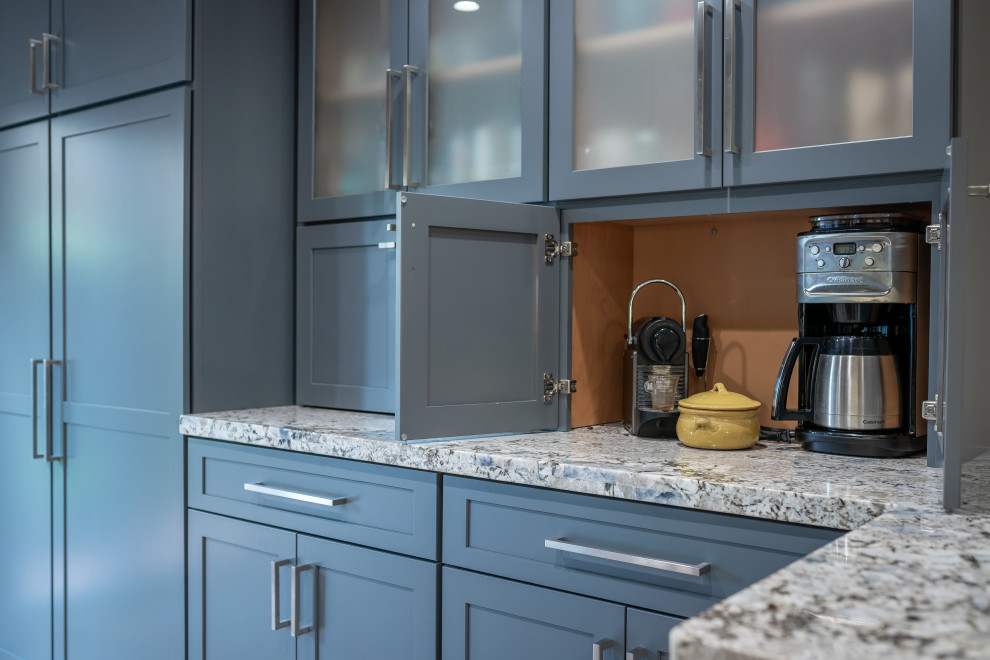 Large country l-shaped kitchen pantry in Miami with a farmhouse sink, shaker cabinets, blue cabinets, granite benchtops, beige splashback, shiplap splashback, stainless steel appliances, vinyl floors, a peninsula, brown floor and multi-coloured benchtop.