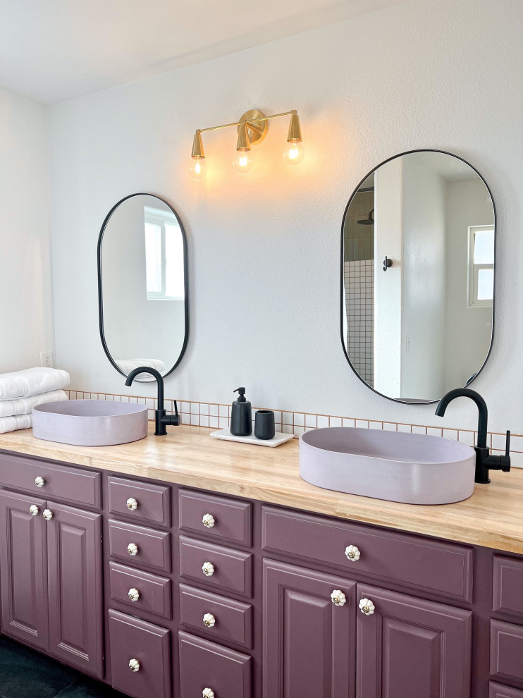 На фото: главная ванная комната в стиле модернизм с фасадами с выступающей филенкой, фиолетовыми фасадами, открытым душем, белой плиткой, керамической плиткой, белыми стенами, полом из сланца, настольной раковиной, столешницей из дерева, черным полом, шторкой для ванной, коричневой столешницей, тумбой под две раковины и встроенной тумбой