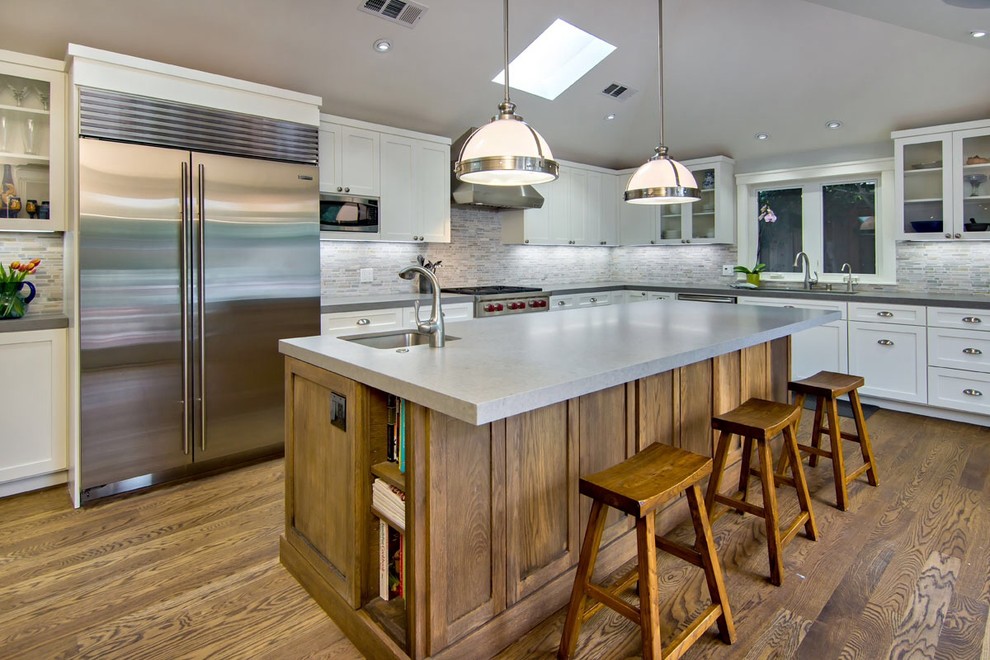 This is an example of a transitional l-shaped eat-in kitchen in San Francisco with shaker cabinets, white cabinets, grey splashback and stainless steel appliances.