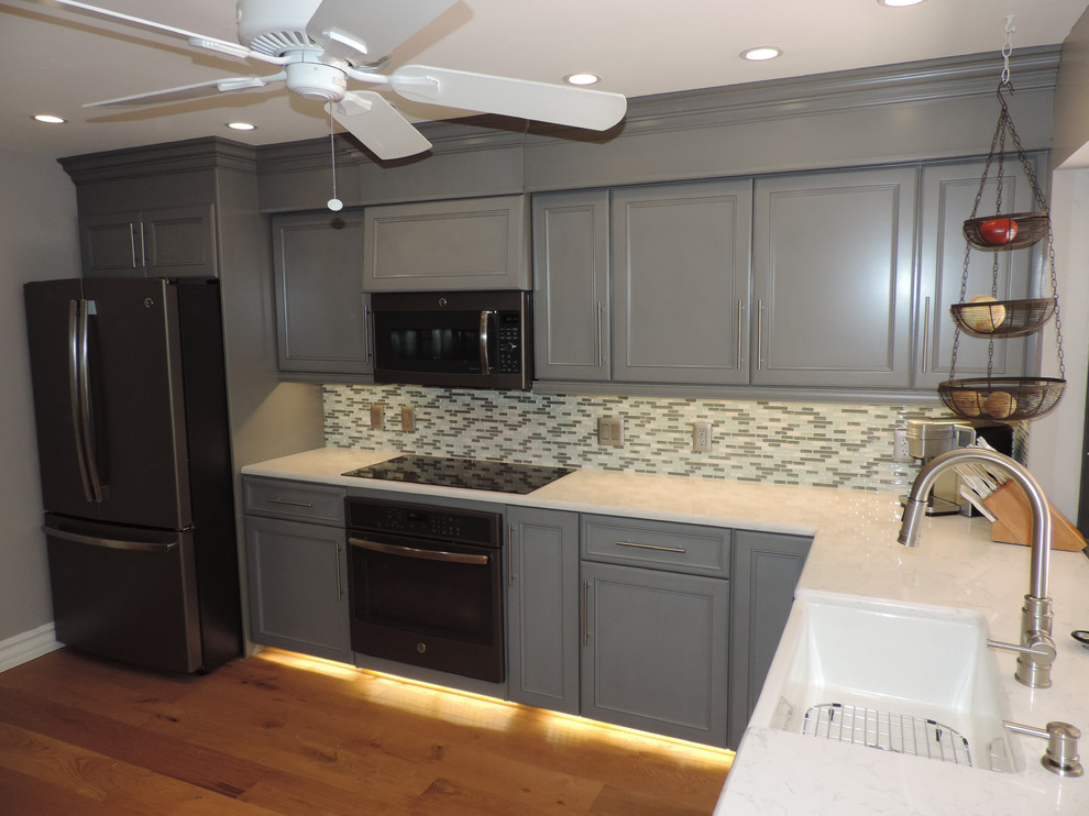 Photo of a mid-sized transitional u-shaped separate kitchen in Miami with a farmhouse sink, recessed-panel cabinets, grey cabinets, granite benchtops, multi-coloured splashback, matchstick tile splashback, white appliances, ceramic floors, no island and brown floor.