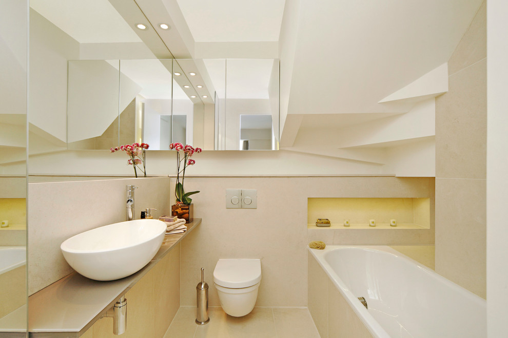 Photo of a contemporary bathroom in London with a vessel sink, an alcove tub, a wall-mount toilet and beige tile.