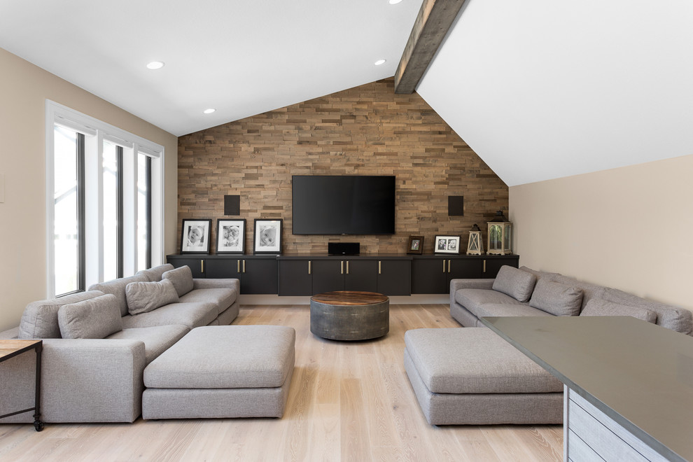 Photo of a transitional family room in Portland with beige walls, light hardwood floors, a wall-mounted tv and beige floor.