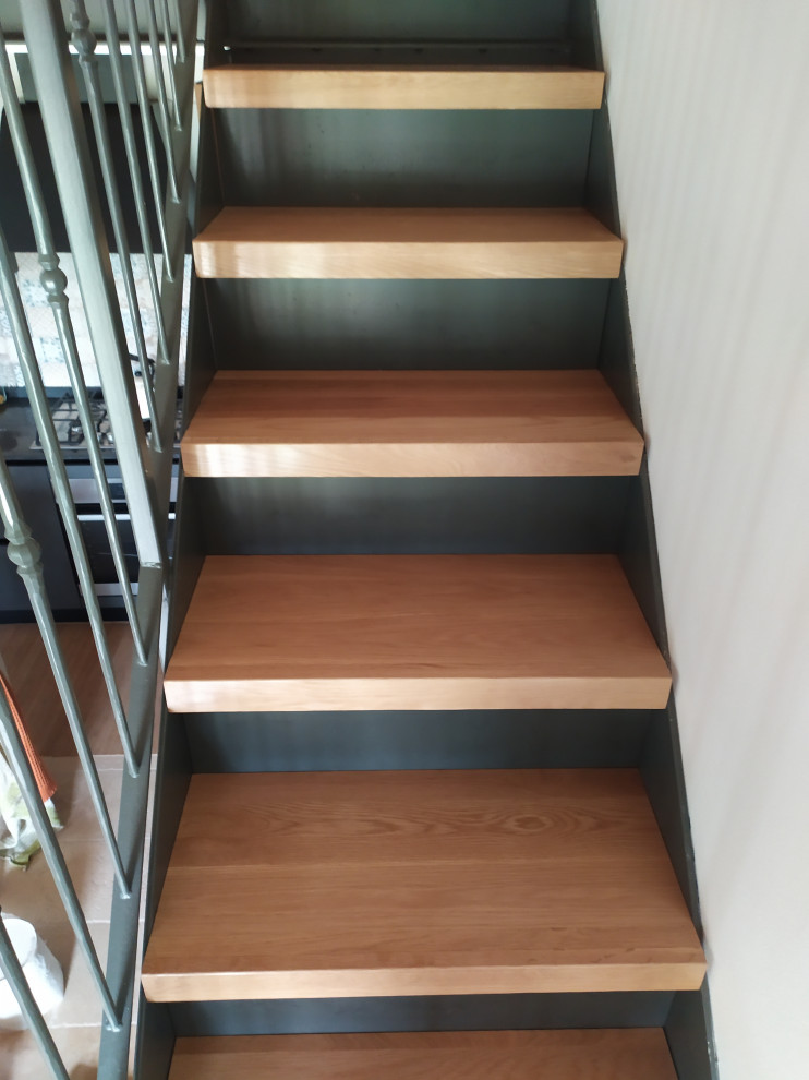 Réalisation d'un escalier design en L de taille moyenne avec des marches en bois, des contremarches en métal et un garde-corps en métal.