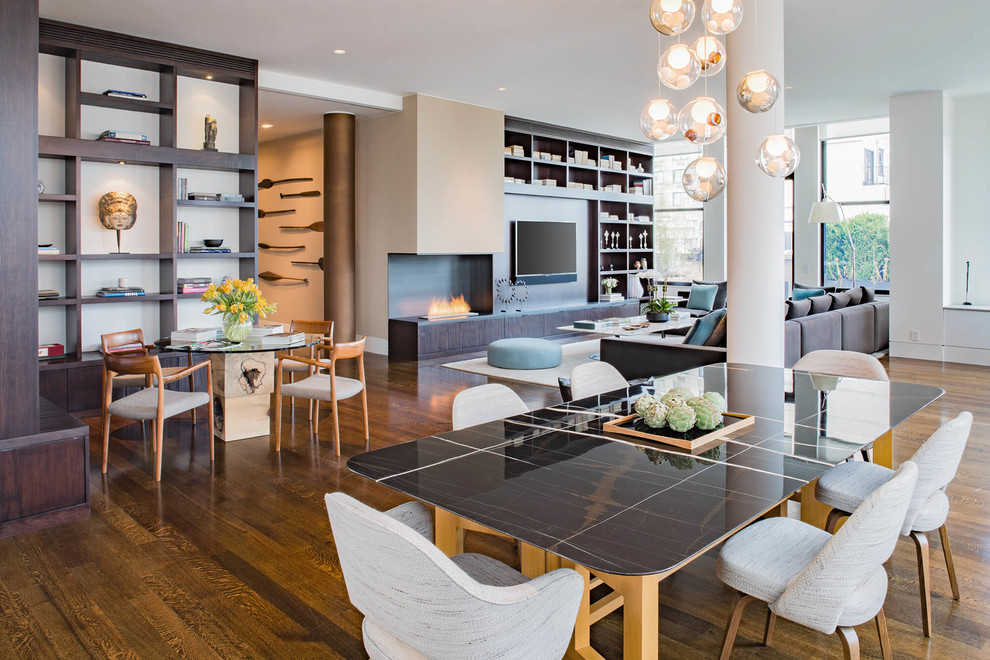 This is an example of a large contemporary open plan dining in New York with white walls, medium hardwood floors, a corner fireplace, a metal fireplace surround and brown floor.