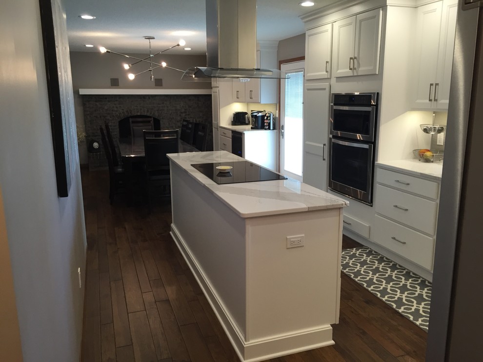 Large transitional l-shaped dark wood floor eat-in kitchen photo with an undermount sink, flat-panel cabinets, white cabinets, quartz countertops, white backsplash, ceramic backsplash, stainless steel appliances and an island