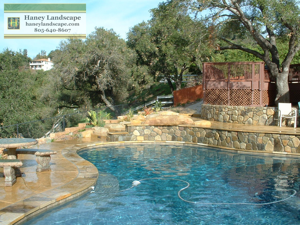 Photo of a mid-sized traditional backyard custom-shaped pool in Santa Barbara with stamped concrete and a hot tub.