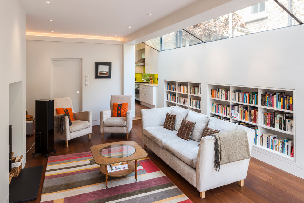 Photo of a contemporary living room in London with a library, white walls and medium hardwood floors.