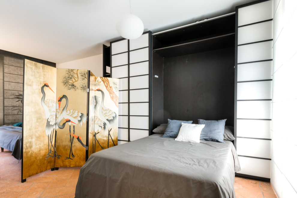 Immagine di una camera da letto stile loft bohémian di medie dimensioni con pareti bianche, pavimento in terracotta, pavimento marrone, soffitto ribassato e carta da parati