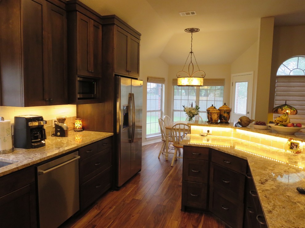 Example of a large transitional medium tone wood floor and brown floor eat-in kitchen design in Austin with an undermount sink, shaker cabinets, dark wood cabinets, granite countertops, multicolored backsplash, ceramic backsplash, stainless steel appliances and an island