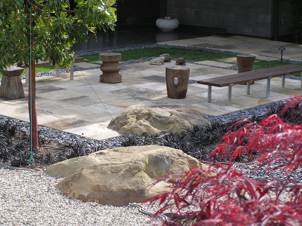 Large modern backyard garden in Santa Barbara with natural stone pavers and with rock feature.