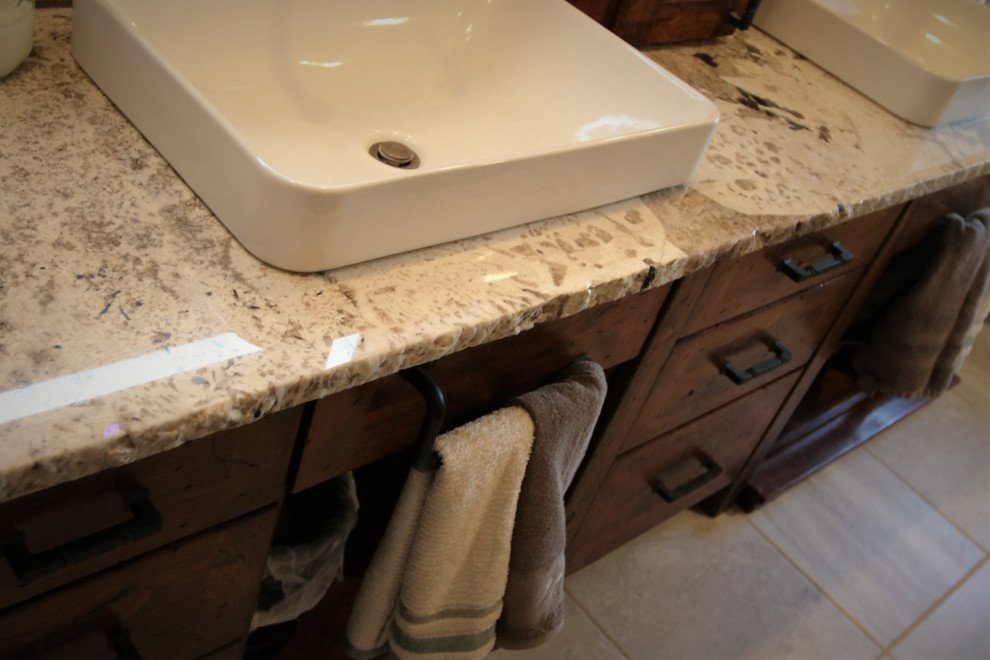 Example of a large mountain style gray tile and stone tile bathroom design with furniture-like cabinets, dark wood cabinets, a vessel sink, granite countertops and white countertops