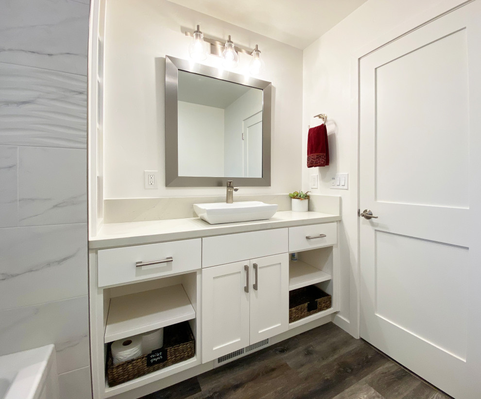 Example of a mid-sized transitional 3/4 black and white tile and porcelain tile vinyl floor, brown floor and single-sink alcove bathtub design with shaker cabinets, white cabinets, a two-piece toilet, white walls, a vessel sink, quartz countertops, a hinged shower door, gray countertops, a niche and a built-in vanity