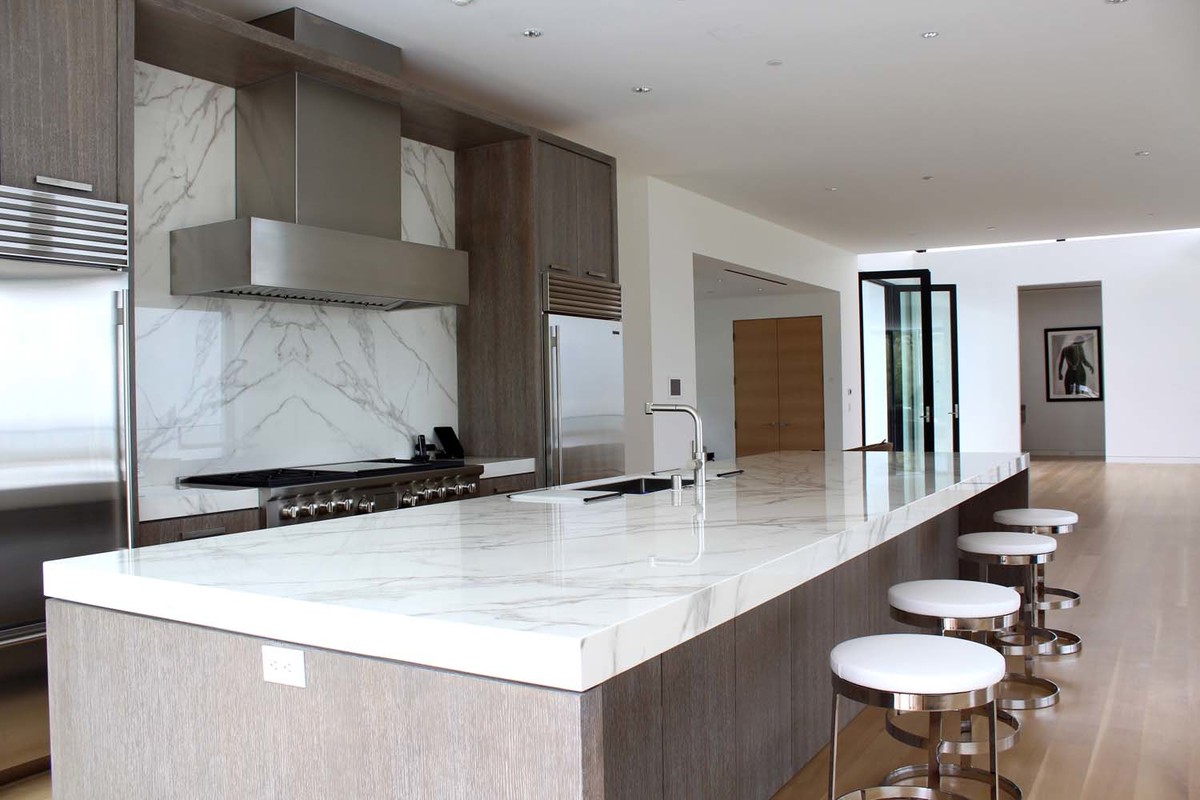 Photo of a large contemporary u-shaped eat-in kitchen in Los Angeles with a double-bowl sink, flat-panel cabinets, grey cabinets, quartz benchtops, white splashback, stainless steel appliances, light hardwood floors, with island and brown floor.