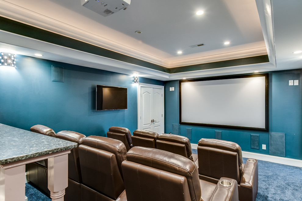 This is an example of a large traditional enclosed home theatre in Charlotte with blue walls, carpet, a projector screen and blue floor.