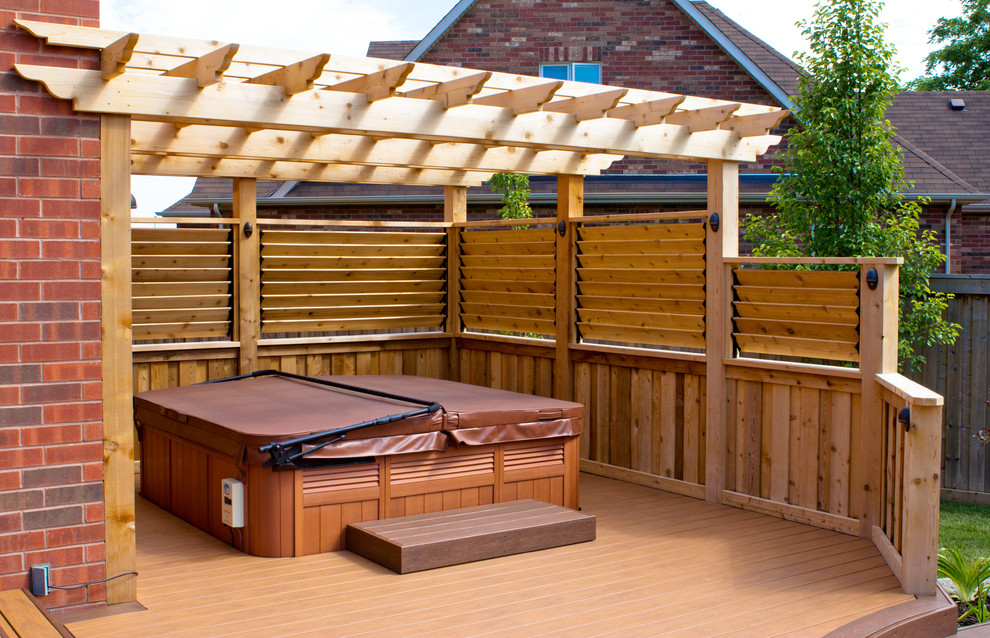 Design ideas for a large modern backyard deck in Toronto with a water feature and a pergola.